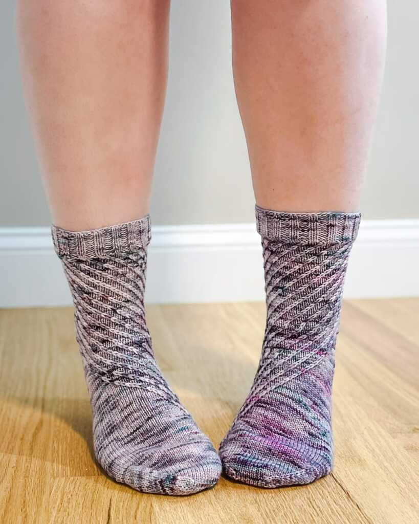 Hand-knit socks made with variegated yarn in a textured diagonal knitting pattern