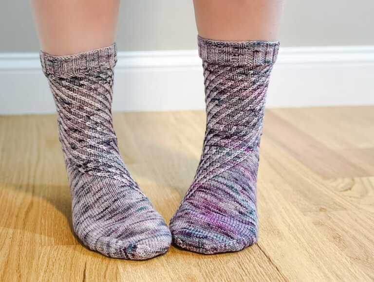 Colorful hand-knitted socks made with variegated sock yarn, featuring a diagonal textured knitting pattern