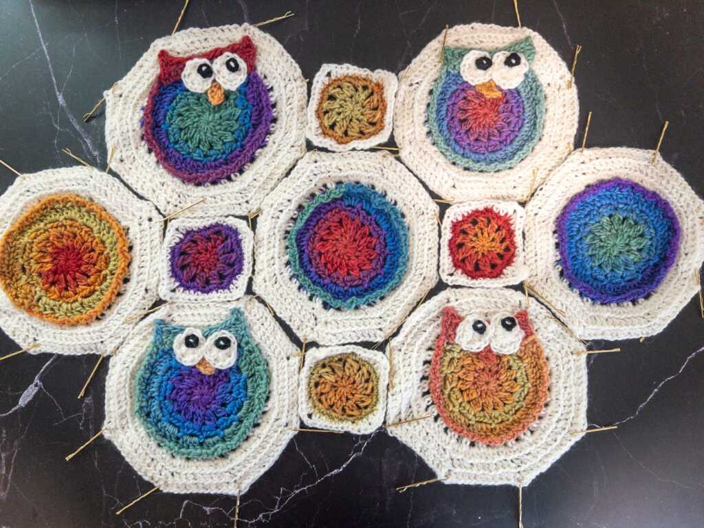 Crochet owl and granny square motifs, handmade with variegated rainbow yarn, pinned for knitting and crochet blocking